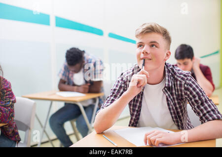 Studente contemplando durante la scrittura del suo esame GCSE Foto Stock