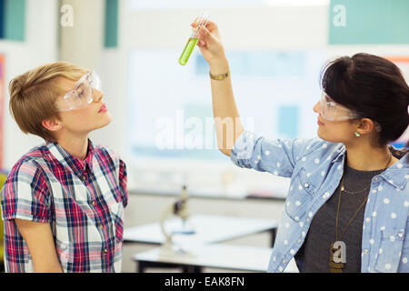 Insegnante e studente durante la lezione di Chimica, indossare occhiali protettivi e guardando il tubo di prova con liquido verde Foto Stock