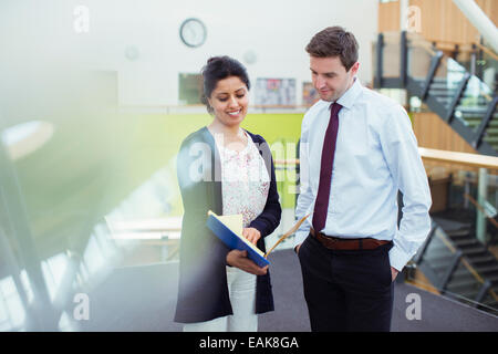 Due insegnanti sorridente parlando nel corridoio in alta scuola Foto Stock