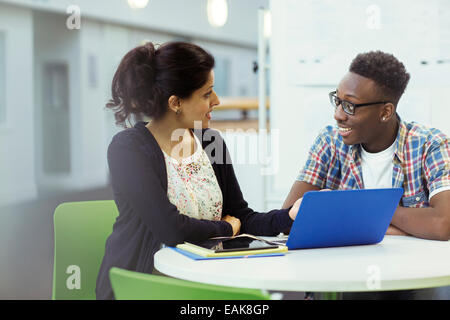 Insegnante e studente seduto insieme con laptop e tablet Foto Stock