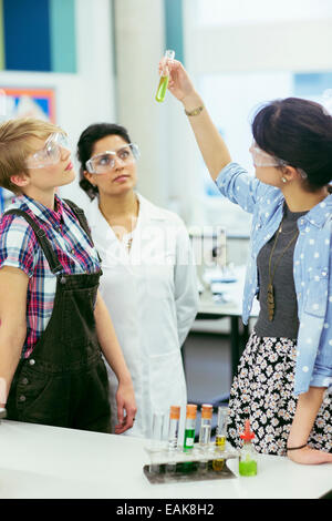 L insegnante e gli studenti durante la lezione di Chimica, indossare occhiali protettivi e guardando il tubo di prova con liquido verde Foto Stock