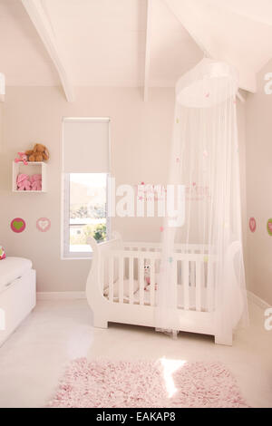 Presepe bianco con tettoia in tulle in color pastello della stanza del bimbo Foto Stock