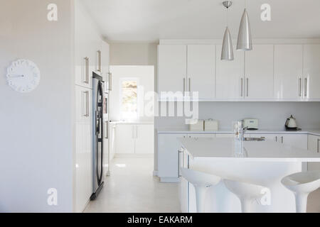 Moderno e di colore bianco e pulire la cucina interno con sgabelli al bancone Foto Stock