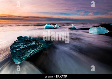 Pezzi di ghiaccio sulla lava nera sulla spiaggia di sabbia di sunrise, Jökularsalon, Vik, Islanda Foto Stock