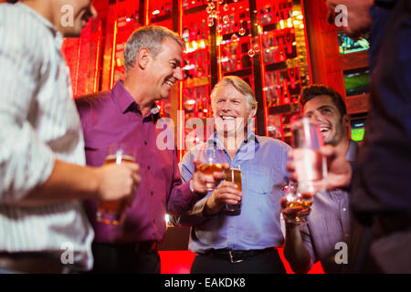 Gruppo di uomini sorridenti avente dei drink al bar Foto Stock