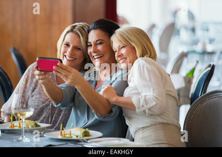 Tre donne mature tenendo selfie nel ristorante Foto Stock