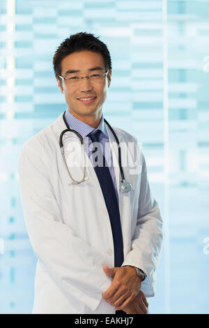 Ritratto di medico sorridente con gli occhiali e camice in piedi in ospedale Foto Stock