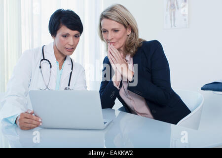 Femmina di medico e paziente utilizzando il computer portatile in ufficio in ospedale Foto Stock