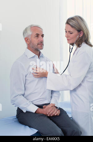 Medico donna esaminando il suo paziente con uno stetoscopio in office Foto Stock