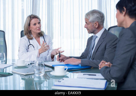 Medico donna, uomo e donna che parlano al tavolo della sala conferenze Foto Stock