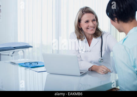 Sorridente medico donna e donna seduta alla scrivania in ufficio Foto Stock