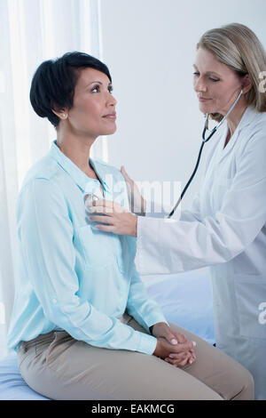 Medico donna esaminando il suo paziente con uno stetoscopio in office Foto Stock