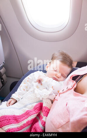 Madre di viaggiare con una di due mesi di età Baby girl su un aereo Foto Stock