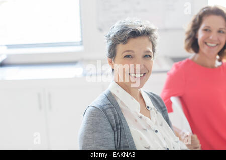 Ritratto di sorridente imprenditrice maturo con il collega in background Foto Stock