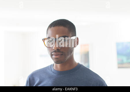 Ritratto di giovane imprenditore con gli occhiali in piedi in ufficio Foto Stock