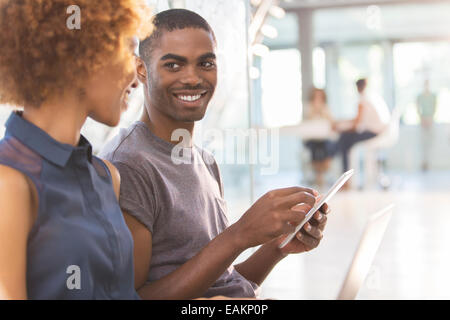 Uomo e donna che utilizza tablet in ufficio, i colleghi in background Foto Stock