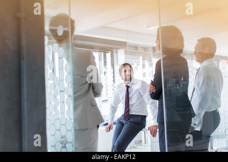 Persone aventi una riunione in ufficio moderno visto attraverso la porta di vetro Foto Stock