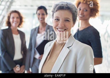 Ritratto di sorridente imprenditrice maturo con team di Office in background Foto Stock