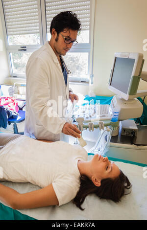 Un bel medico utilizzando una macchina ad ultrasuoni sulla gola di una giovane ragazza Foto Stock