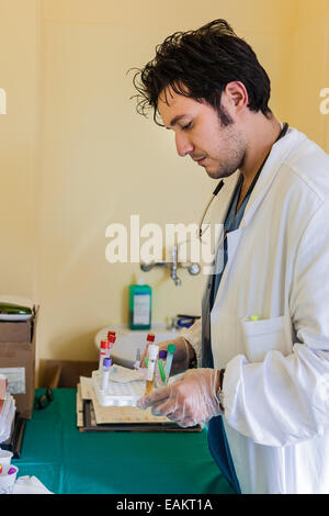 Un giovane e bello medico tenendo un vassoio con i campioni di sangue Foto Stock