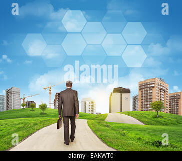 Imprenditore passeggiate sulla strada. Vista posteriore. Edifici, campo di erba e cielo con esagoni Foto Stock