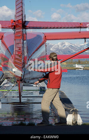 Pilota con la ruggine's Flying Service prepara il suo piano per il volo sul Lago di cofano in Anchorage in Alaska, Foto Stock