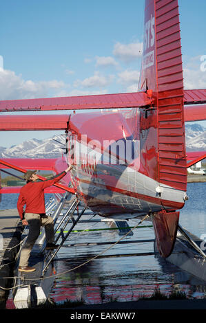 Pilota con la ruggine's Flying Service prepara il suo piano per il volo sul Lago di cofano in Anchorage in Alaska, Foto Stock