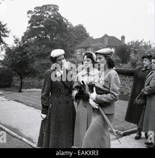 Anni '1950, immagine storica che mostra tre attraenti giovani donne in piedi insieme all'esterno, elegantemente vestite con abiti alla moda del giorno, con cappelli, cappotti e borse, Inghilterra, Regno Unito. Foto Stock