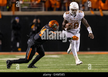 15 novembre 2104: Texas Longhorns quarterback Tyrone Swoopes (18) gira la sfera come Oklahoma State Cowboys linebacker Josh Furman (14) i tentativi di rendere il paranco durante il NCAA Football il gioco tra la Oklahoma State Cowboys e la Texas Longhorns a Boone Pickens Stadium di Stillwater, OK. I giocatori del Longhorn sconfitto il cowboy 28-7. Foto Stock