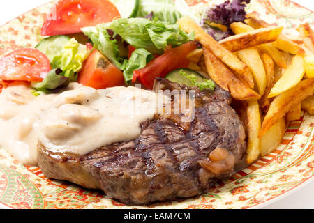 Nervatura alla griglia-eye bistecca di manzo servita con salsa di funghi, insalata e patatine. Foto Stock