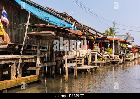 Hovels di un piccolo villaggio sulla riva di un canale nella campagna tailandese nel distretto di Ratchaburi, Thailandia Foto Stock