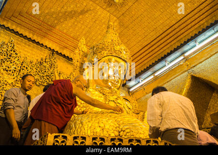 Applicazione di foglia oro al Grande Buddha dorato, Mahamuni statua uno di il più venerato Buddha in Birmania.Mandalay, Birmania,Myanmar. Foto Stock