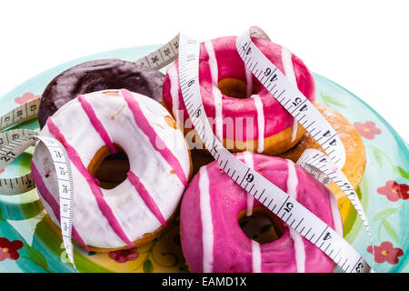 Alcuni deliziosi e ciambelle colorate con nastro di misurazione Foto Stock