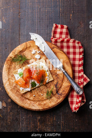 In Sandwich di pane croccante con salmone affumicato e morbida crema di formaggio di oliva sulla piastra di legno Foto Stock