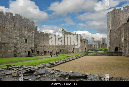 Vasto spettacolare interno del XIII secolo Caernarfon Castle con enormi pareti & alte torri intorno al cortile erboso sotto il cielo blu Foto Stock