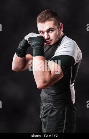 Un giovane kickboxer o boxer in posa su uno sfondo scuro Foto Stock