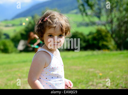 Primo piano di una graziosa bambina in giardino e lei guarda la fotocamera Foto Stock