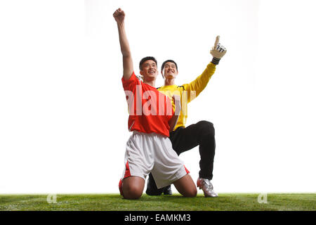 Due calciatori festeggiare il successo si inginocchiava sull'erba Foto Stock