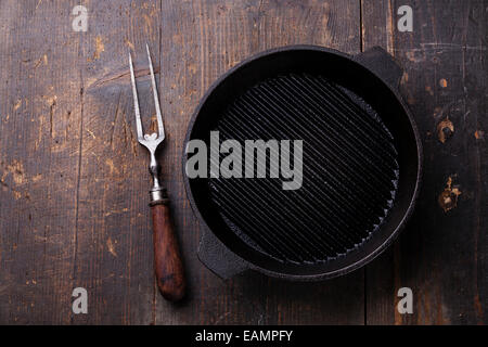 Nero vuota ferro padella per grigliare carne e sulla forcella di legno sfondo texture Foto Stock