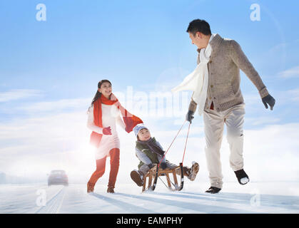 Una famiglia di tre persone a giocare nella neve Foto Stock