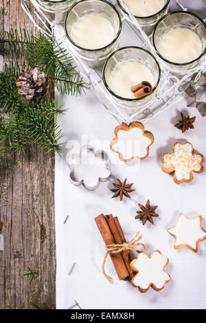 Biscotti di Natale assortiti e bicchieri di latte cocktail serviti con albero di natale ramo sul tavolo di legno. Foto Stock