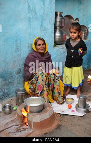 India Rajasthan, regione di Mewar, Bundi village, donna alla preparazione del cibo e il bambino Foto Stock