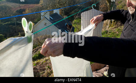 Una donna senior di stendere il bucato su una linea di lavaggio al di fuori in autunno il sole in Carmarthenshire Wales UK KATHY DEWITT Foto Stock