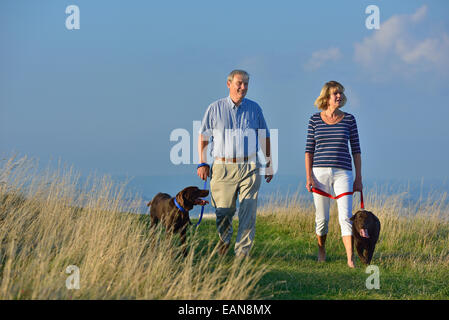 Una coppia matura a piedi i loro cani sulla South Downs, Eastbourne. East Sussex, Regno Unito Foto Stock