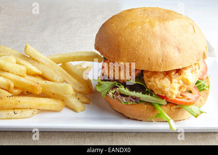 Shrimp Po Boy con patatine fritte su una piastra bianca con striscia rossa panno della tabella Foto Stock