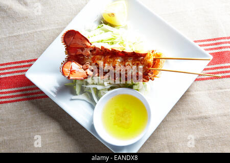 Principale di coda di aragosta infilzato nel guscio flash withe fritto di burro al limone e limoni e lattuga Foto Stock