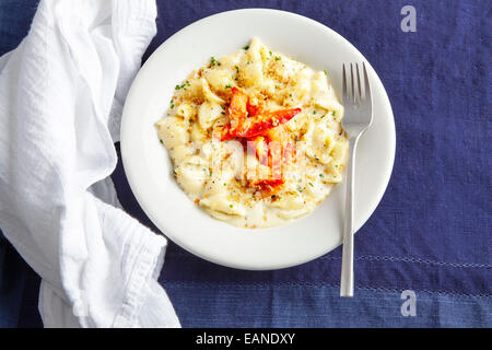 Lobster Mac e formaggio in una piastra bianca con tovagliolo bianco e blu navy tovaglia Foto Stock