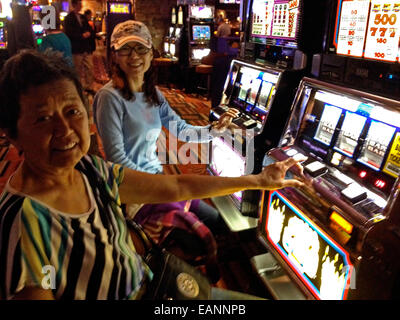 Due donne cinesi turisti che giocano slot machine a Los Vegas Casinò Foto Stock