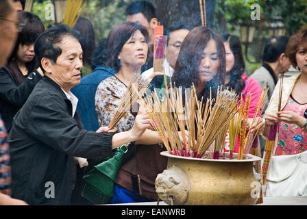 Le donne di incenso di alleggerimento in Wong Tai Sin Temple di Kowloon, Hong Kong, Cina. Foto Stock