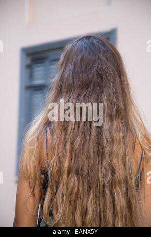 Vista posteriore di una giovane donna con capelli lunghi marrone in piedi all'aperto Foto Stock